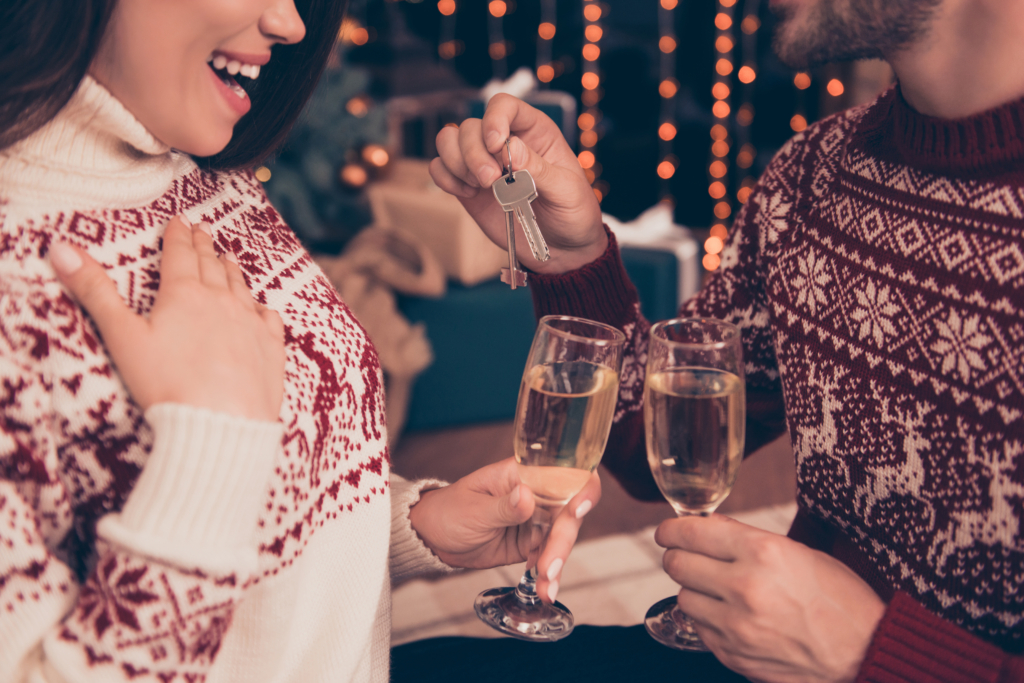 Couple at Christmastime cheering with Champagne with a new house key