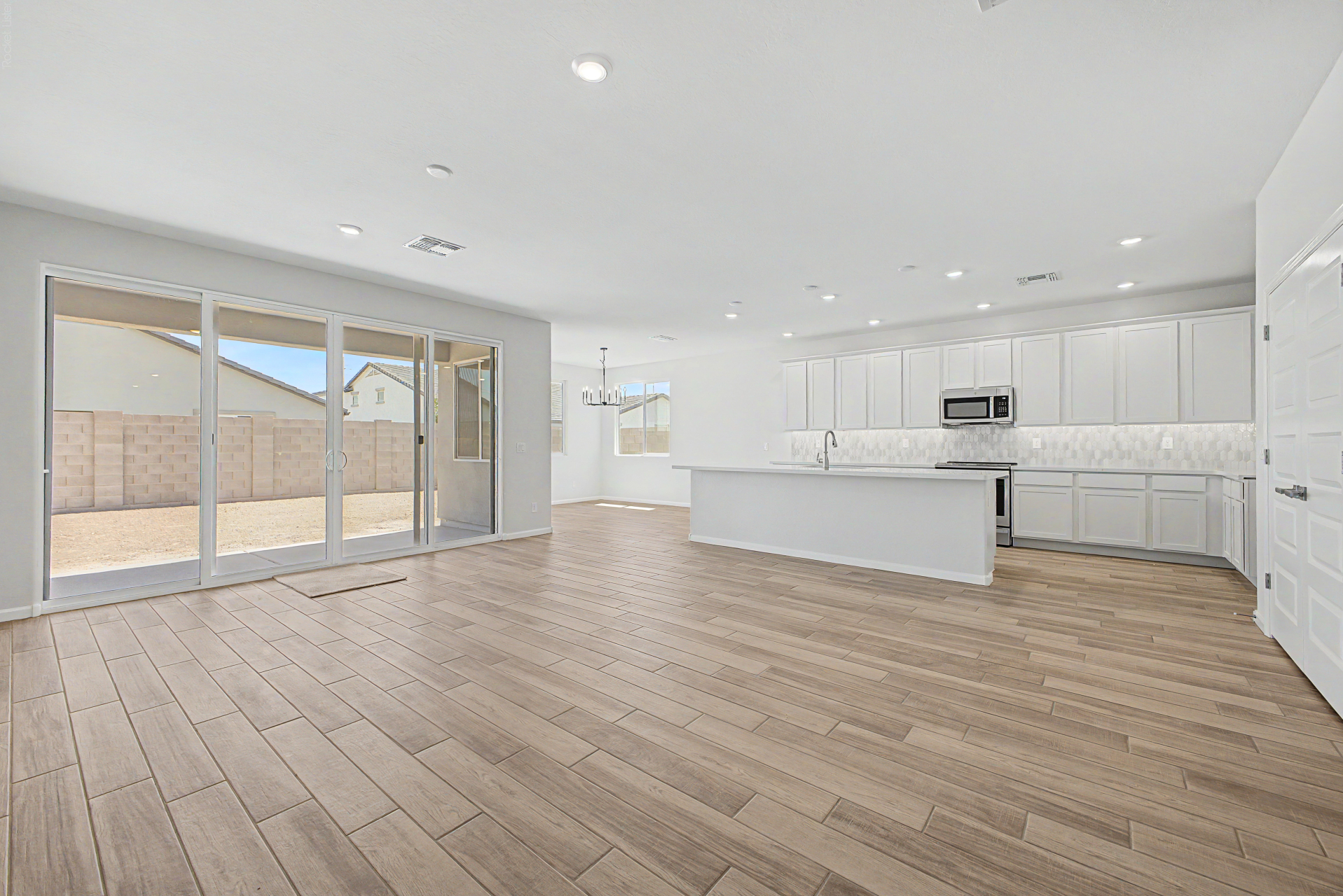 Great room view of a violet 4414 floor plan featuring white cabinets and a large sliding glass door