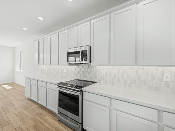 kitchen of a violet 4414 floor plan featuring upgraded appliances and a tiled backsplash