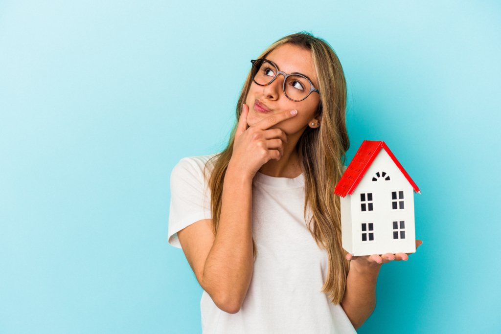 Girl holding a house toy and thinking